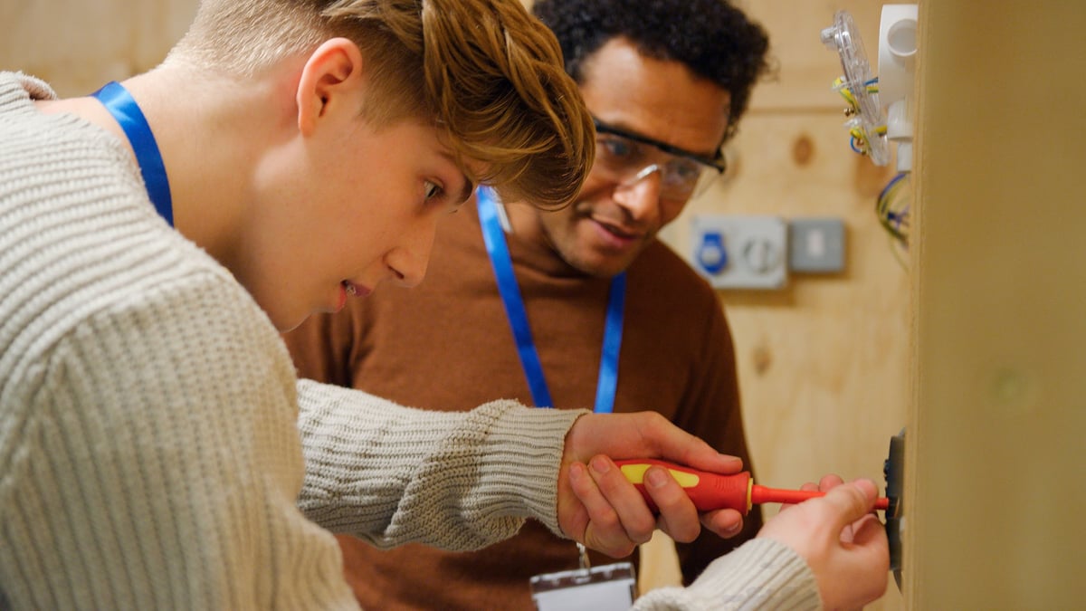 A tutor guiding students through practical work in a workshop