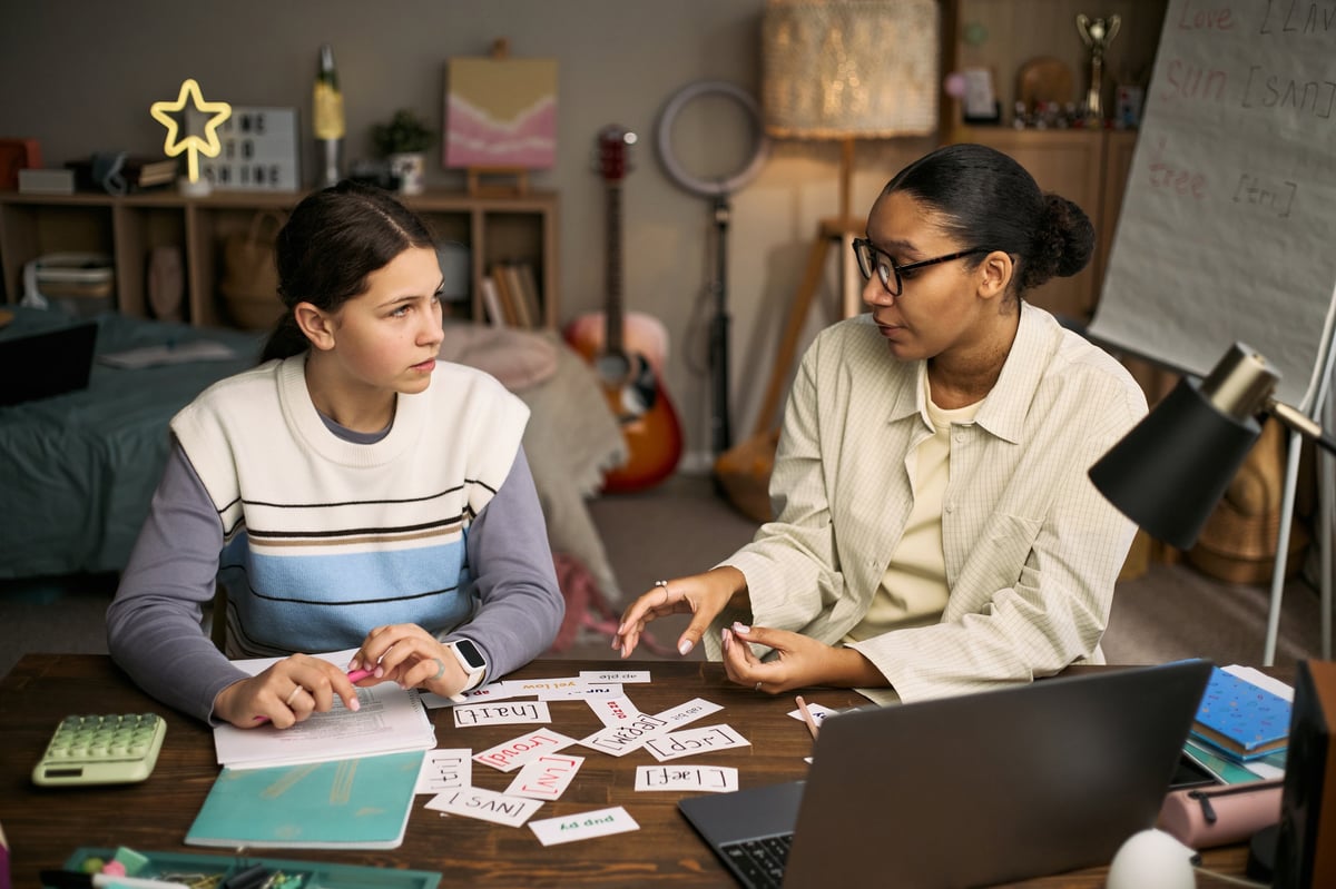 A teenage student learning from a tutor using word cards