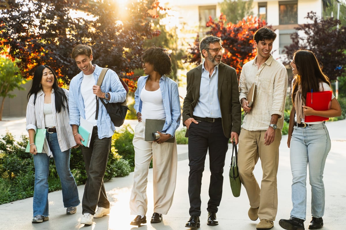 Happy students walking on a university campus with a professor