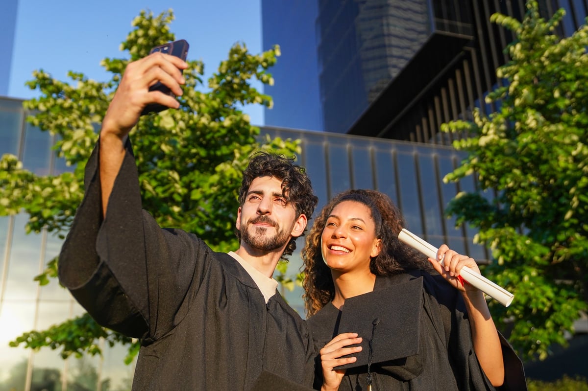 Two young students celebrating together with a diploma